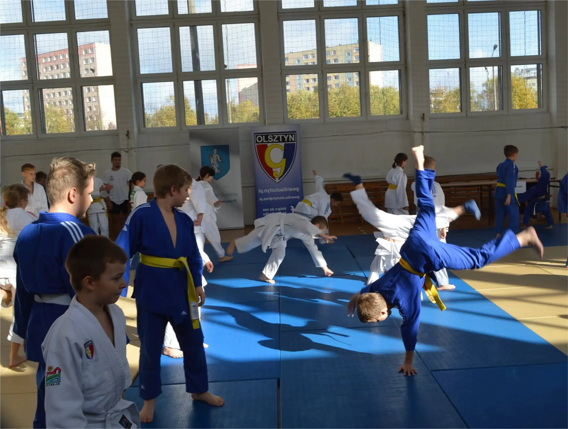 Zawodnicy ćwiczą rzuty na macie podczas treningu w dojo