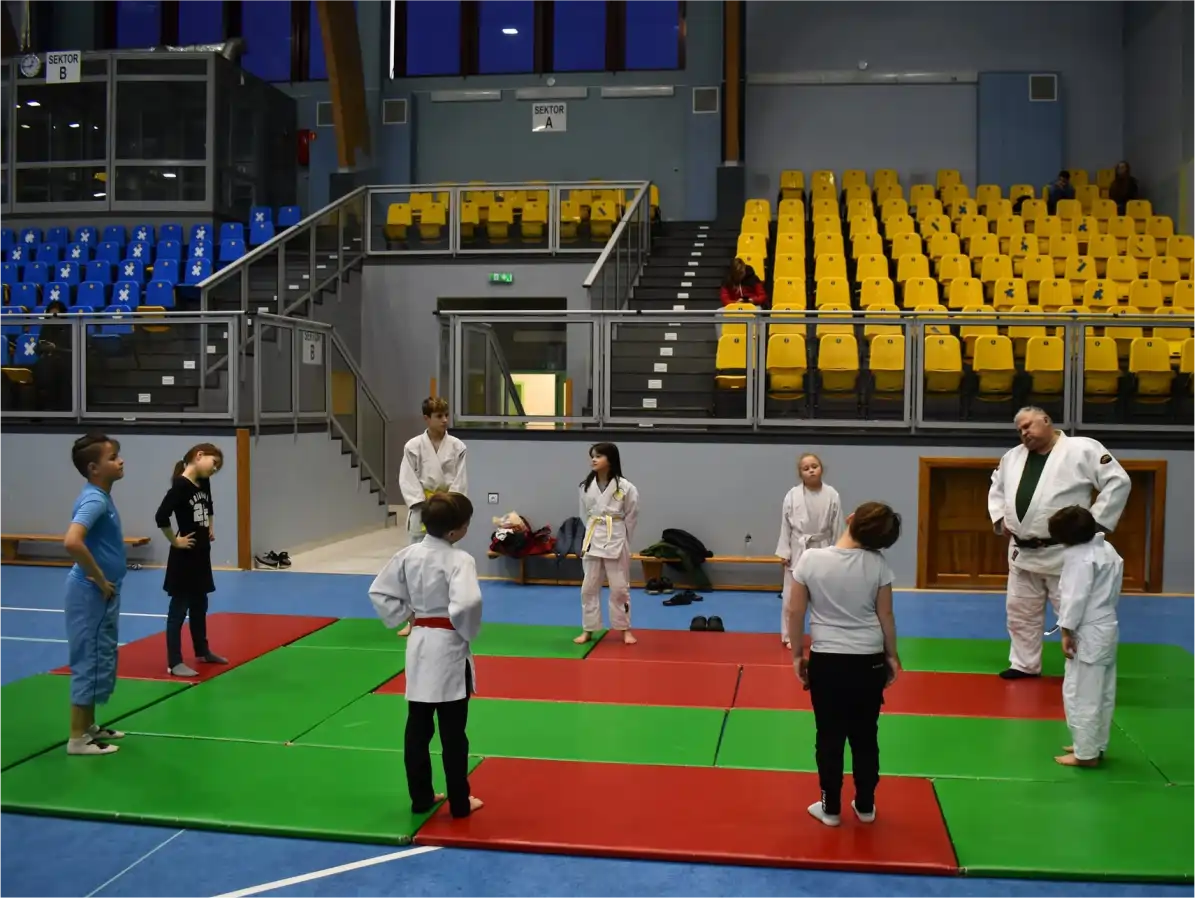 Instruktor prowadzi zajęcia z dziećmi w strojach judo